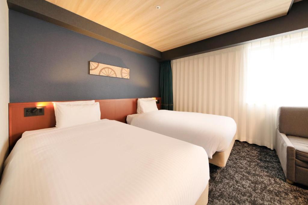 two beds in a room with a window at Richmond Hotel Yokohama-Bashamichi in Yokohama
