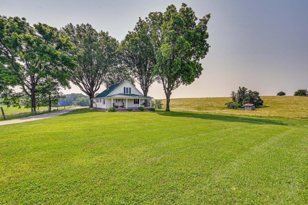 una casa en un gran campo de césped con árboles en Dobson Farmhouse with Scenic Porch - Near Vineyards!, en Dobson