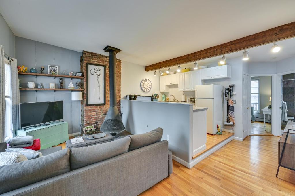 Cozy Boston Vacation Rental with Rooftop Deck! في بوسطن: غرفة معيشة مع أريكة ومطبخ