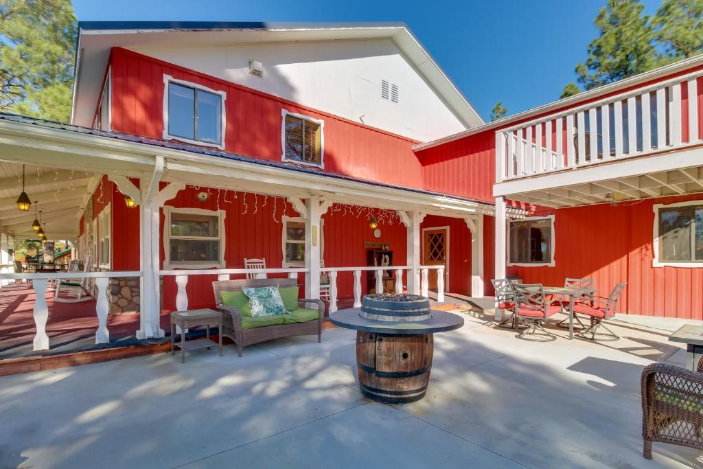 une maison rouge avec une table sur une terrasse dans l'établissement High Country Farmhouse Near Sitgreaves Natl Park!, à Overgaard