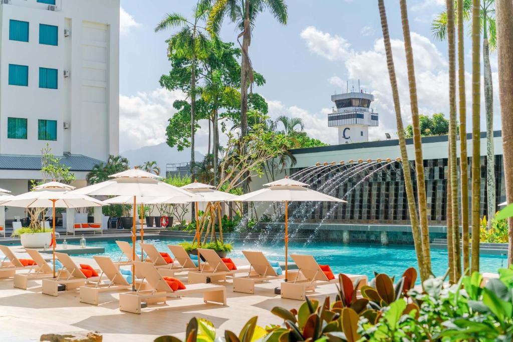 珍南海灘的住宿－Wings by Croske Resort Langkawi，一座带躺椅和遮阳伞的游泳池位于大楼旁