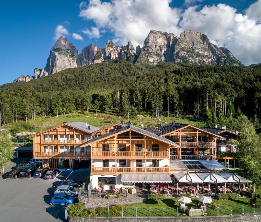 une vue aérienne sur un hôtel avec des montagnes en arrière-plan dans l'établissement Dolmites Nature Hotel Vigilerhof, à Alpe di Siusi