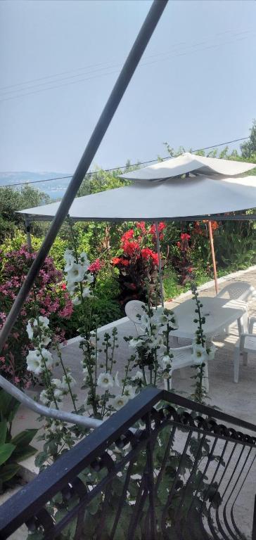 a table with a white umbrella and some flowers at Raymondos Apartments in Lassi