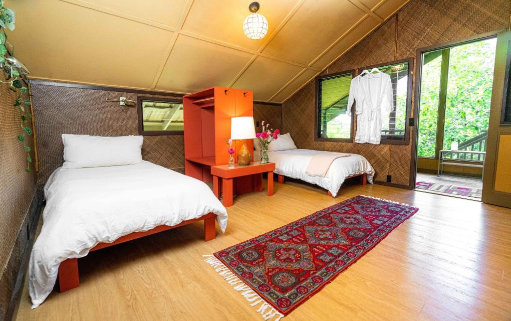a room with two beds and a rug at Hamakua Sanctuary in Honokaa