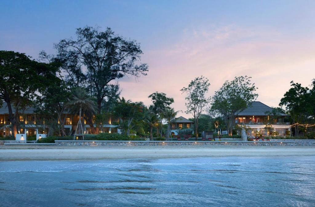 a view of a beach with houses in the background at Charras Bhawan Hotel and Residences in Hua Hin