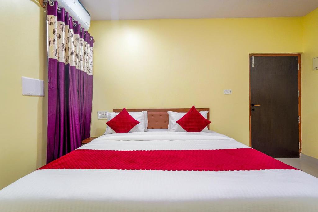 een slaapkamer met een groot wit bed met rode kussens bij SRI VIJAYA PALACE LODGING in Bangalore