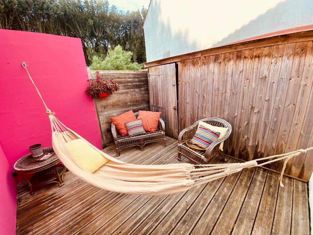 a hammock and two chairs on a deck at Maison de plage à 100m de la mer in Talmont
