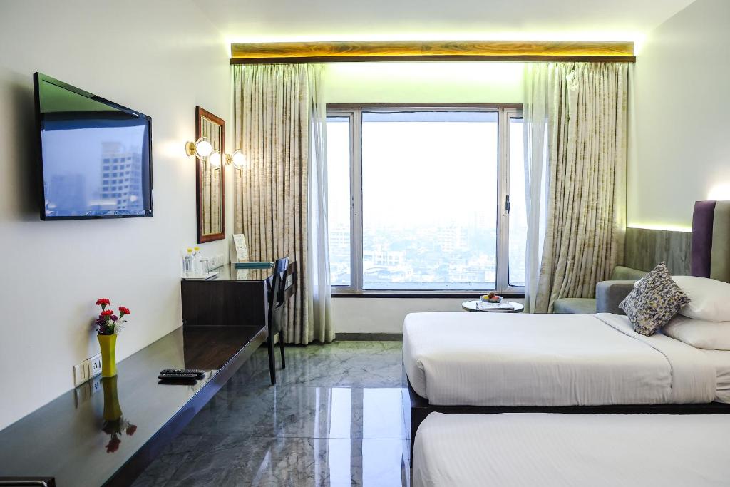 a hotel room with a bed and a large window at Krishna Palace Hotel in Mumbai