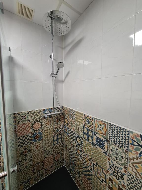 a bathroom with a shower with mosaic tiles on the wall at Pension Die kleine Auszeit in Denia