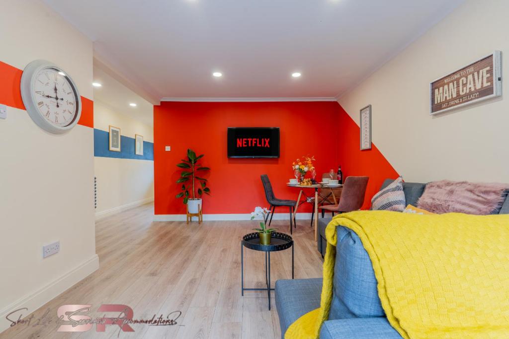 a living room with a red wall and a table at Stylish One Bed House with Private Garden and Free Parking in Northolt