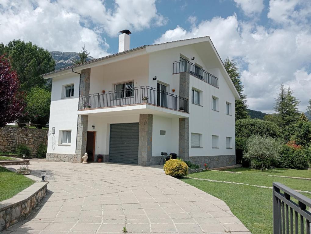 ein weißes Haus mit einem Balkon und einer Auffahrt in der Unterkunft Apartamento-Casa turística l'Espígol in San Lorenzo de Morunys