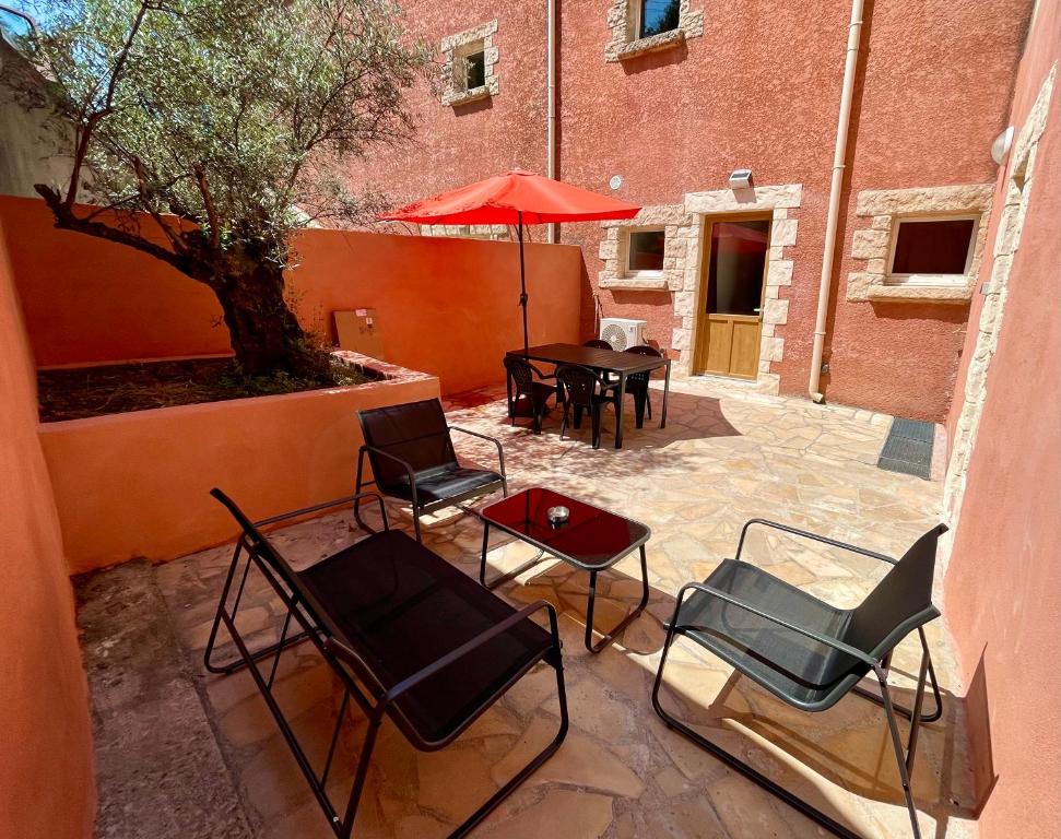 une terrasse avec des chaises, une table et un parasol dans l'établissement Studio Coin nuit 205 Résidence Les Acacias, à Anduze