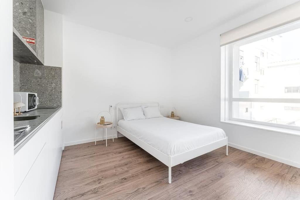 um quarto branco com uma cama e uma janela em GuestReady - Magnolia Apartments - Studio 2 no Porto