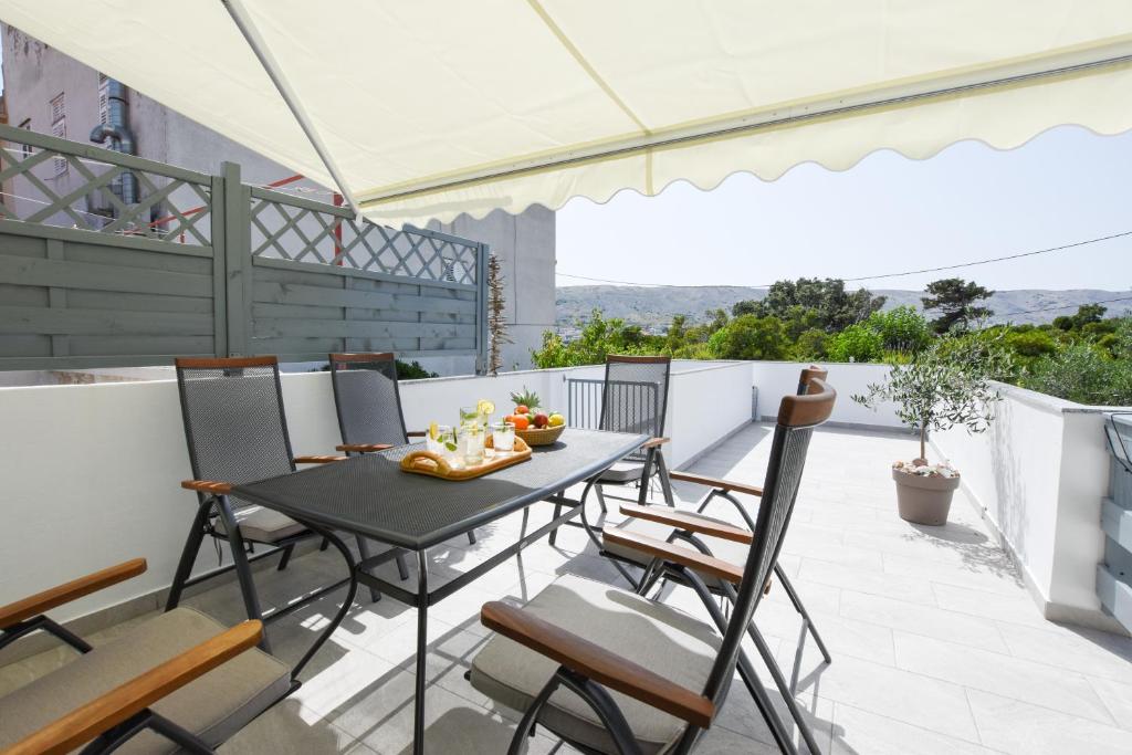 patio con mesa y sillas en el balcón en Apartment Sidro en Pag