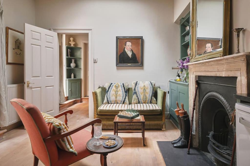 a living room with two chairs and a fireplace at Bath's Most Illustrious Address - Garden Apartment in Bath