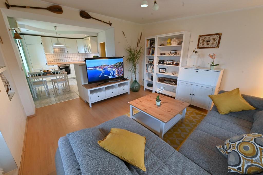a living room with a blue couch and a television at Captain's Cabin Piran - free parking in Piran