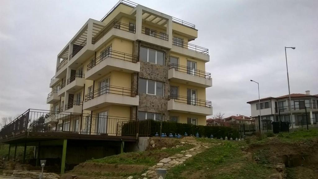 a tall yellow building with balconies on a hill at Апартаменты за гости Гаван in Byala