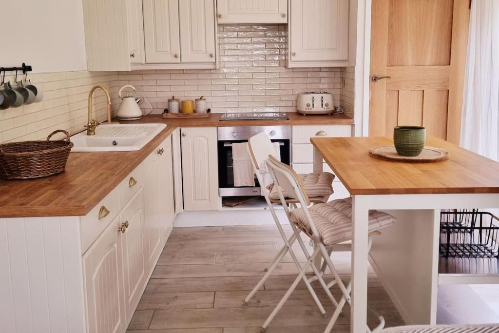 uma cozinha com armários brancos e uma mesa com cadeiras em Relaxing retreat near Norfolk Broads em Norwich