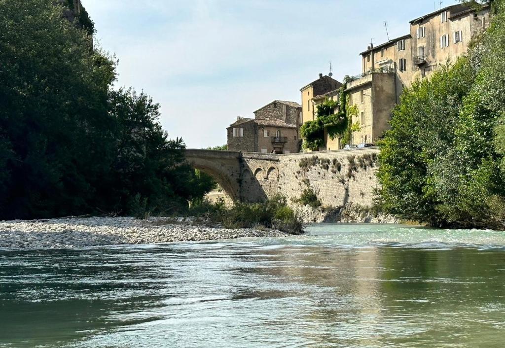 een rivier met een brug en gebouwen op de achtergrond bij Sur le Pont in Vaison-la-Romaine