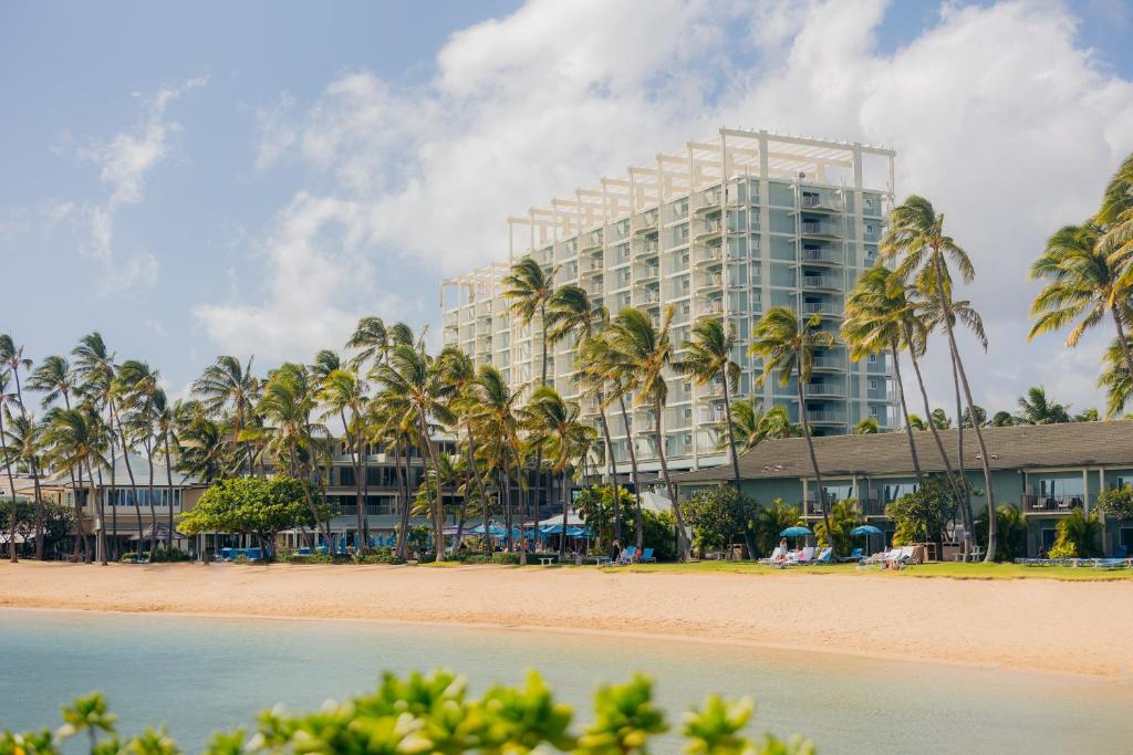 ホノルルにあるThe Kahala Hotel and Resortのヤシの木が茂るビーチ沿いのホテル