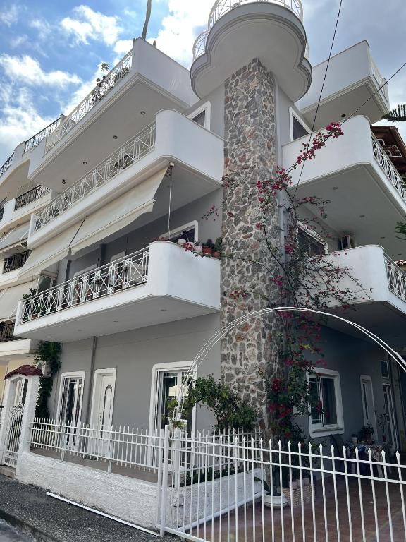 a white building with a white fence in front of it at Mairi’s Apartment in Nea Artaki