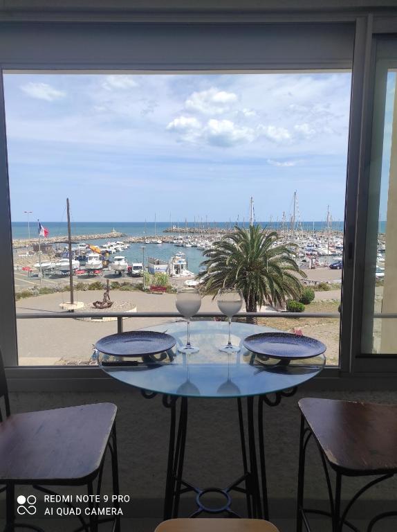 einen Tisch mit Weingläsern auf einem Balkon mit Hafenblick in der Unterkunft Appartement vue mer in Narbonne-Plage
