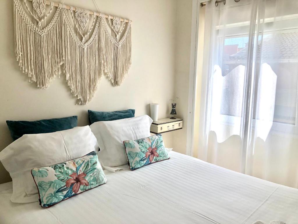 een wit bed met 2 kussens en een raam bij Casa Clara in Aveiro