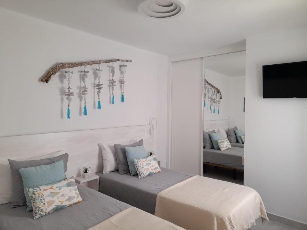 sypialnia z 2 łóżkami, telewizorem i lustrem w obiekcie Bungalow La Palmera - 2 bedroom - PLAYA ROCA residence sea front access - Pool View - Free AC - Wifi w Costa Teguise
