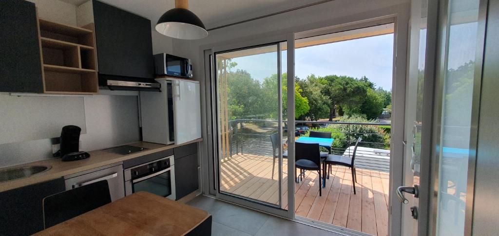 a kitchen with a sliding glass door leading to a deck at Résidence Salamandre - Maison Bois Cosy Calme avec parking pour 4 à 10 pers idéal couples et familles à 500m de la plage à Saint-Marc-sur-mer in Saint-Nazaire