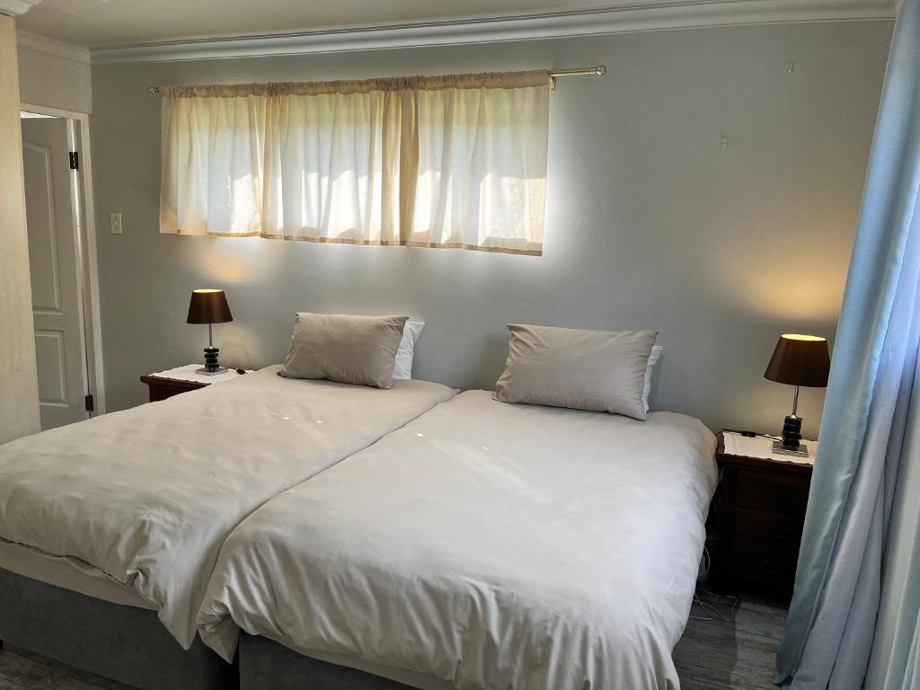 a bedroom with a bed with white sheets and two lamps at Dux in Montagu