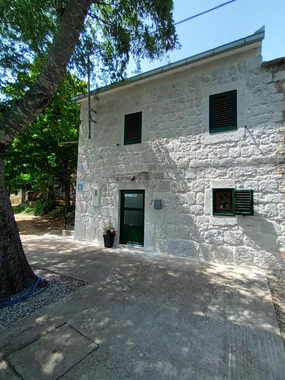 ein weißes Steingebäude mit einer Tür und einem Baum in der Unterkunft Kuća za odmor Grupković in Ploče