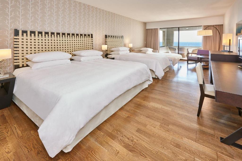 a hotel room with three beds and a desk at Sheraton Rhodes Resort in Ixia