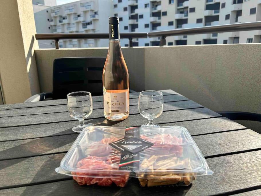 a bottle of wine and two glasses on a table at BARCABEACH front de mer avec terrasse et parking in Le Barcarès