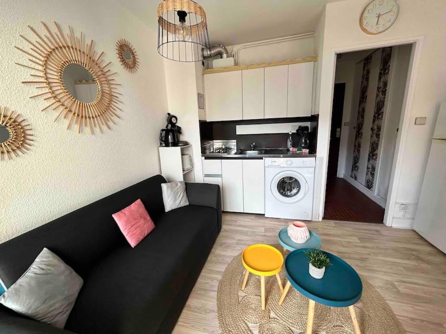 a living room with a black couch and a table at BARCABEACH front de mer avec terrasse et parking in Le Barcarès