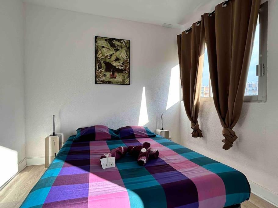 a teddy bear on a colorful bed in a bedroom at BARCABEACH front de mer avec terrasse et parking in Le Barcarès