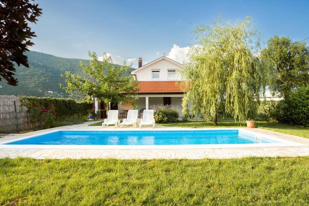 uma piscina num quintal com duas cadeiras e uma casa em Holiday Home Vemini em Mostar