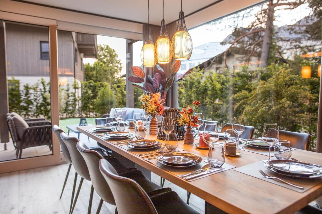 a long wooden table with chairs and a large window at Boutique ChaletS Alpi - Private Sauna & Cinema in Garmisch-Partenkirchen