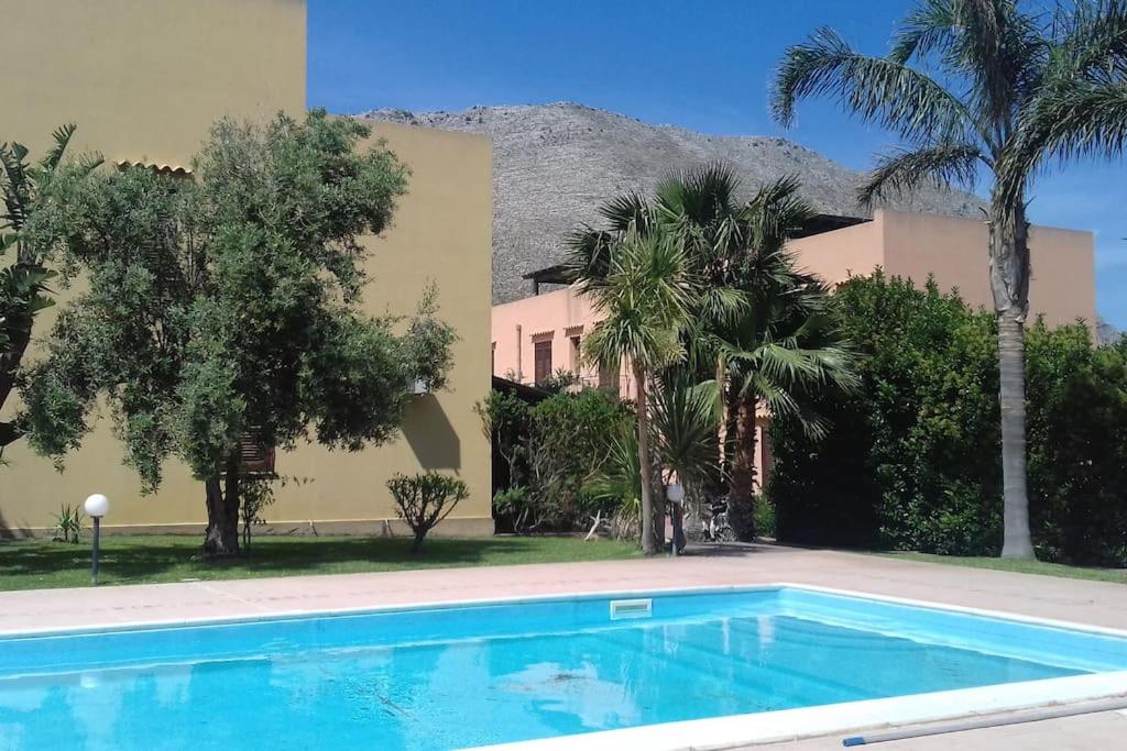 een zwembad voor een gebouw met palmbomen bij Villetta Casa Rosa in Castelluzzo