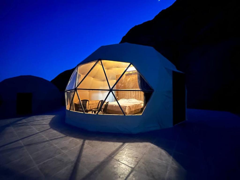 Wild Oryx Camp Bubbles في وادي رم: خيمة صغيرة مع نافذة زجاجية في غرفة مظلمة