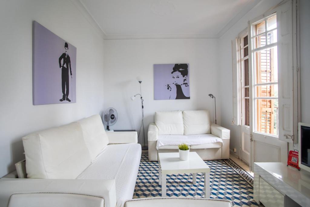 a white living room with two white couches and a table at 42par1049 - Super Bright 3BR in Sant Antoni in Barcelona