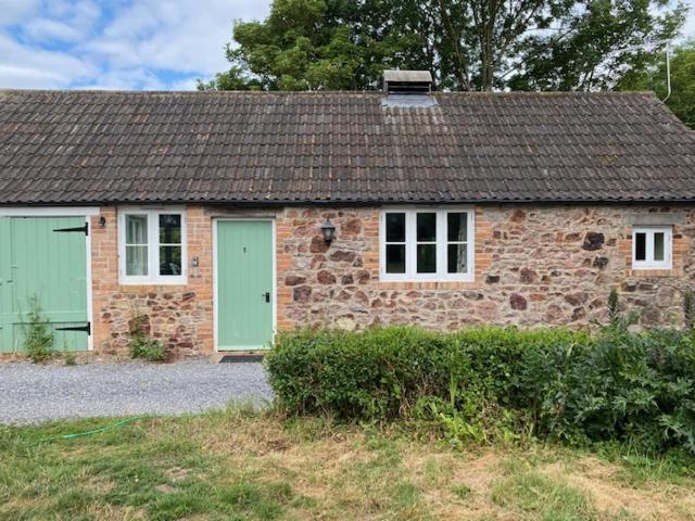 a brick house with a green door and a stone at Lodge 1, The Grange in Wick