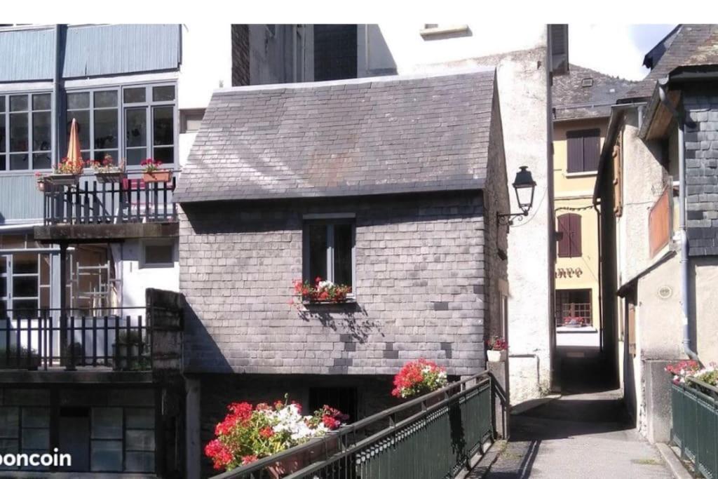 a small brick building with flowers on a balcony at La « cabaneste » dans Arreau in Arreau