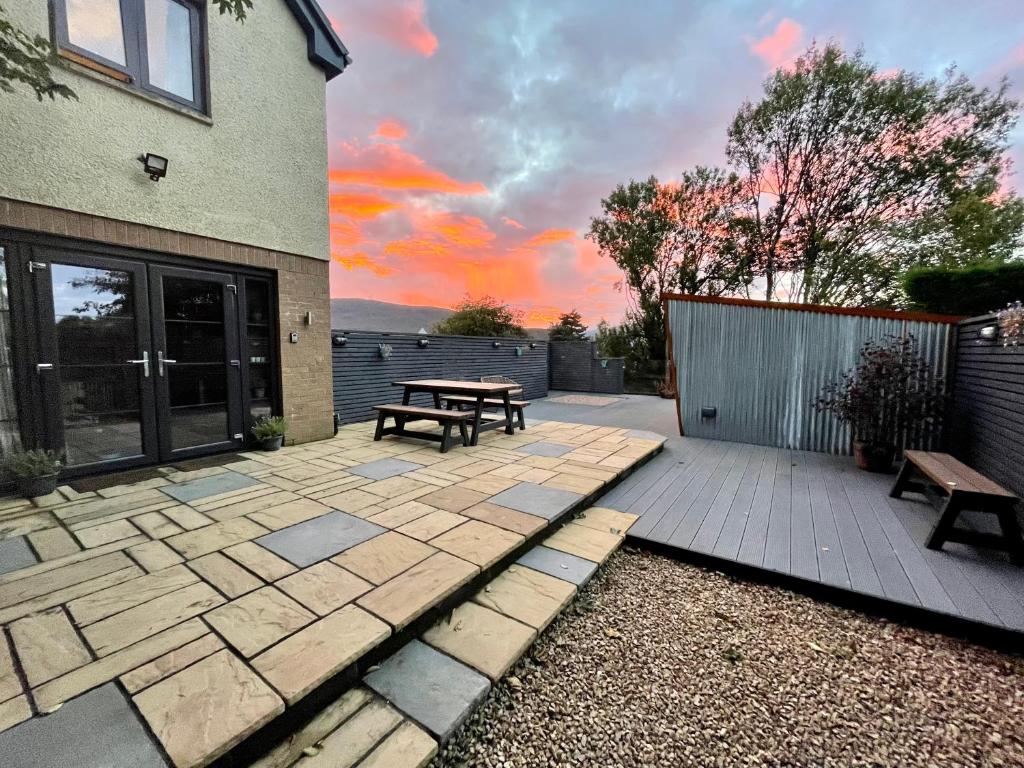 a patio with a picnic table and benches in front of a house at Stylish, central studio with kitchen & large deck in Fort William