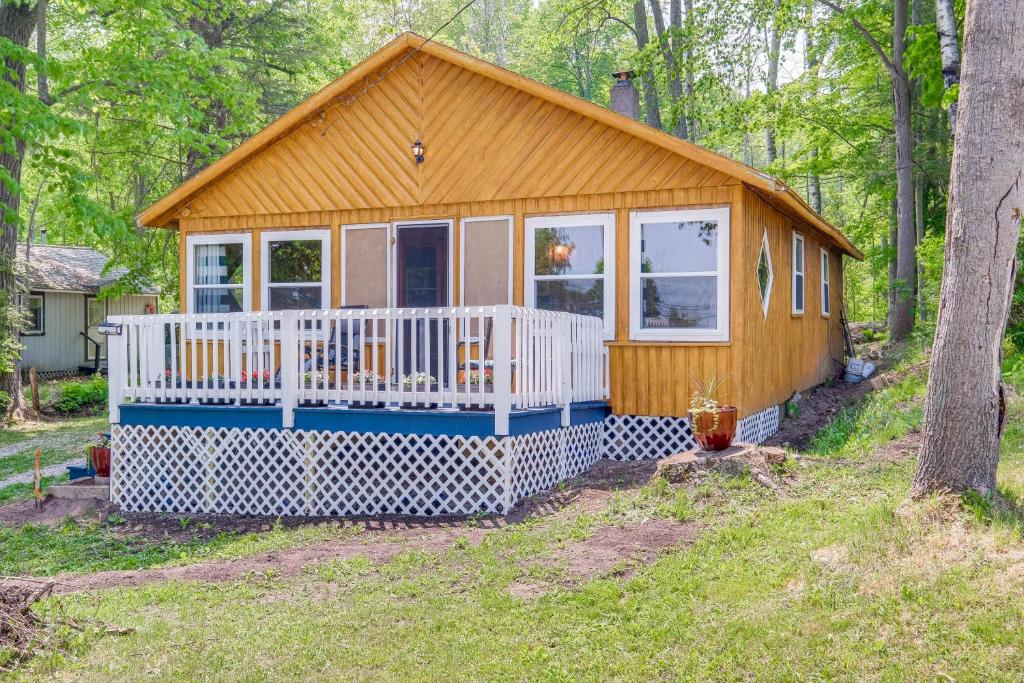 a tiny house in the woods with a porch at Charming Michigan Cottage with Sunroom and Lake Access in Hubbard Lake