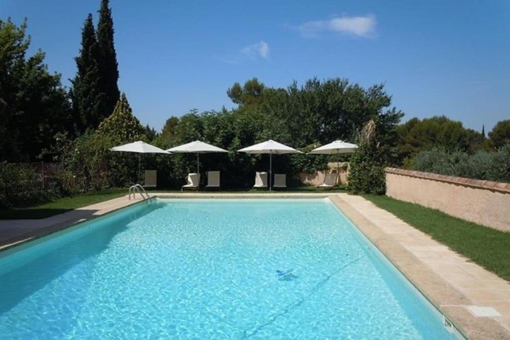 - une grande piscine avec parasols dans une cour dans l'établissement Agréable maison de 65 m2 avec grande piscine, à Aix-en-Provence