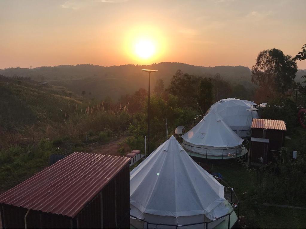 two tents in a field with the sunset in the background at สวนภูซีเขาค้อ in Ban Pa Daeng