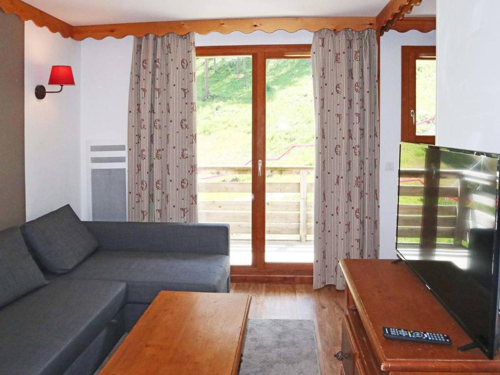un salon avec un canapé et une grande fenêtre dans l'établissement Appartement charmant avec piscine, sauna, et accès skis aux pieds - 6 personnes, Les Orres 1800 - FR-1-322-446, aux Orres