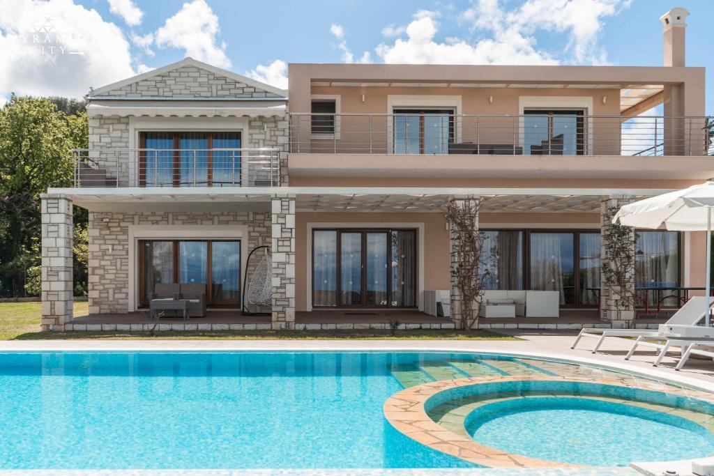 a house with a swimming pool in front of it at Luxury Villa Hera - Beachfront in Roda