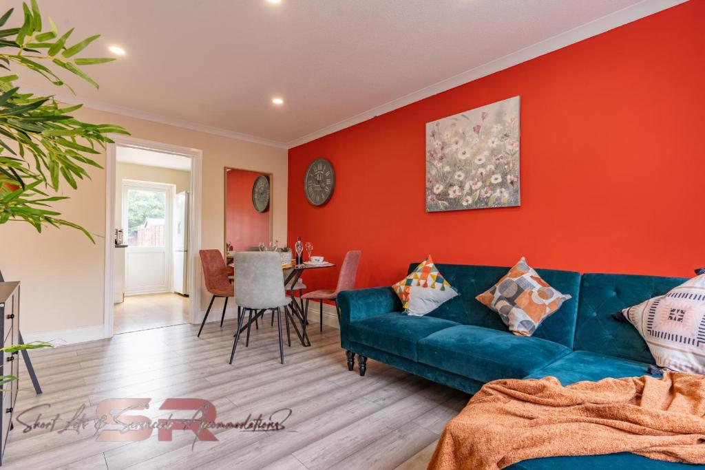 a living room with a blue couch and a red wall at Rush House by SR Short Lets & Serviced Accommodation Heathrow Windsor - Perfect for Monthly Stay Relocation & Business Contractors Big Groups in Northolt