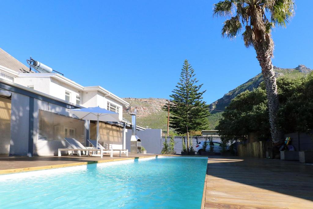 a swimming pool next to a house with a palm tree at THE PLACE Muizenberg in Muizenberg